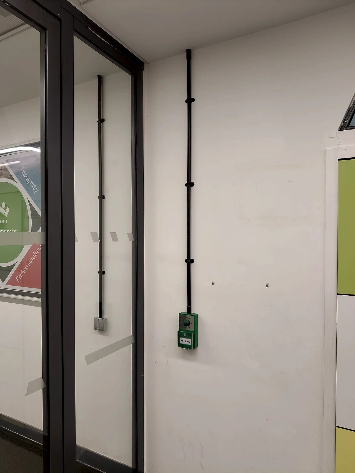 Access control and emergency exit button installed beside a glazed door